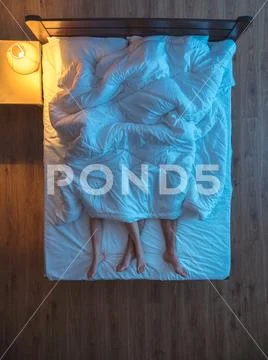 The couple lay under cover on the bed. evening night time. view from above Stock Photos