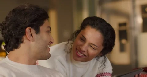 Couple leaning on couch wearing sweaters, watching tablet playing funny clip, Stock Footage 339268570