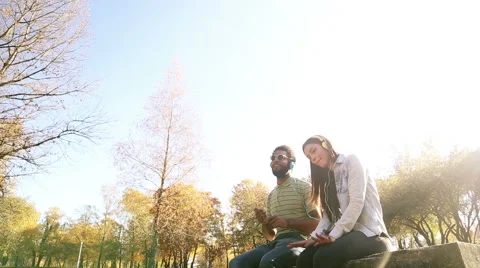Couple listening to music on headphones while hanging out in park Stock Footage 59554741