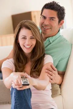 Couple in living room with remote control smiling Stock Photos