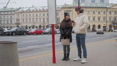 Couple looking for bus information on a schedule at a city street stop Stock Footage 311461504