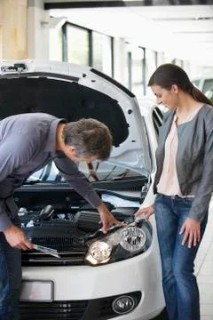 Couple looking at a car engine in a showroom Stock Photos