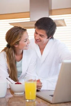 Couple looking at each other while using laptop over breakfast Fotos Stock