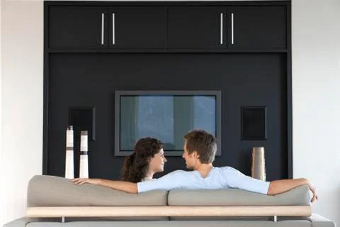 Couple Looking At Each Other While Relaxing On Couch Stock Photos