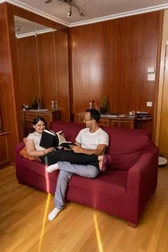 Couple looking at each other while reading books at home laying relaxed on a  Stock Photos