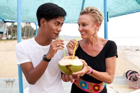 Couple looking to each other while sharing a natural coconut to drink in a beach Stock Photos