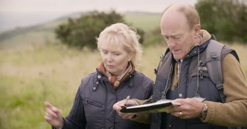 Couple looking at gps device in field Stock Footage 59899615