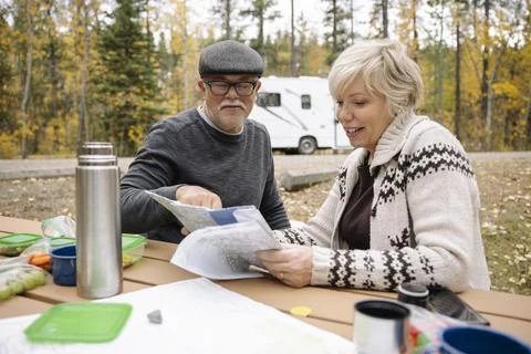 Couple looking at map on picnic table in front of RV Fotos Stock