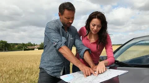 Couple looking at road map on car hood Stock Footage 14831976