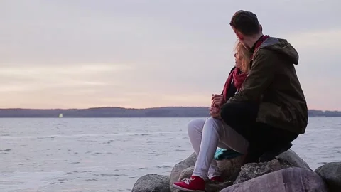 Couple looking at sea while sitting on rock Video stock 168840793