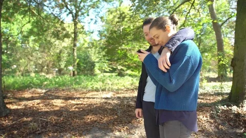 Couple looking at smartphone while strolling through park Stock Footage 75189738