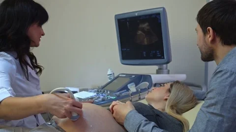 Couple looking at ultrasound scan of baby on tablet pc on sofa Stock Footage