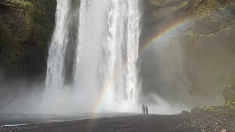 Couple Looks Tiny Next to Huge Waterfall in Iceland with Rainbow Video stock 273455691