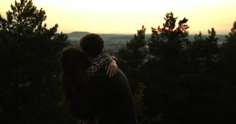 A couple in love embrace while standing on the edge of a cliff at sunset. Stock Footage 264488553