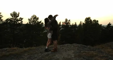 A couple in love embrace while standing on the edge of a cliff at sunset. Stock Footage 264488555