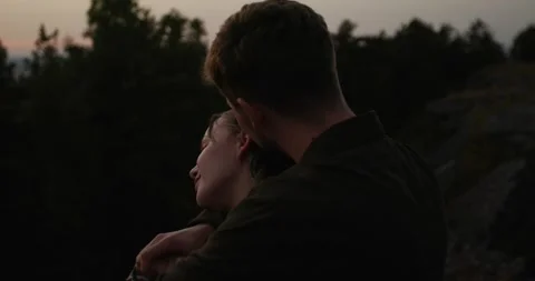 A couple in love embrace while standing on the edge of a cliff at sunset. Stock Footage 264488560