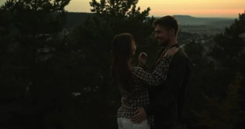 A couple in love embrace while standing on the edge of a cliff at sunset. Stock Footage 264488562
