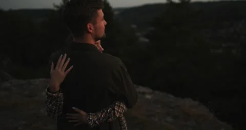 A couple in love embrace while standing on the edge of a cliff at sunset. Stock Footage 264488583
