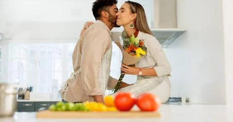 Couple love, flowers and happy cooking together in kitchen at home, romanc... Stock Photos