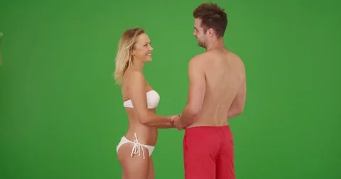 Couple in love holding hands and talking in their swimsuits on green screen Stock Footage