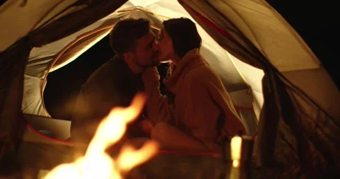 Couple in love hugging while sitting in a tent near a campfire at night. Stock Footage 264488687