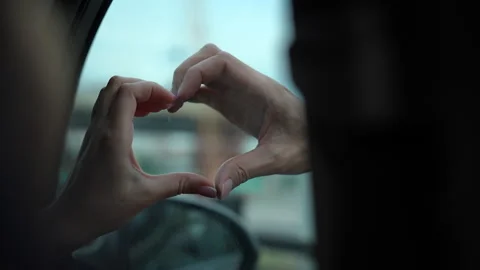 Couple in love making heart shape with their hands sitting inside car during Stock Footage 342759077