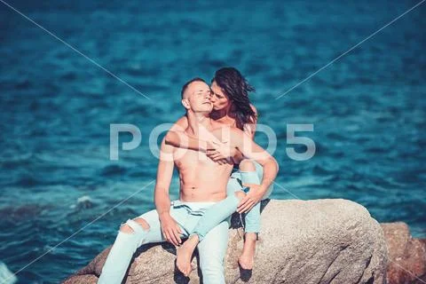 Couple in love relax on beach stone. couple in love suntan topless in jeans at Stock Photos