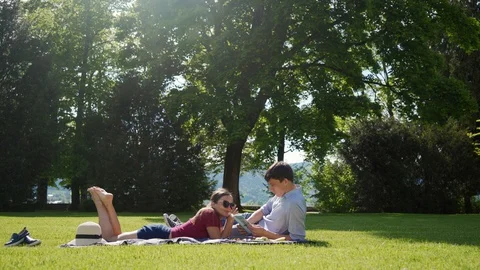 Couple in love relax on lawn while picnic. Guy reading his girl interesting book 库存影片 127785503