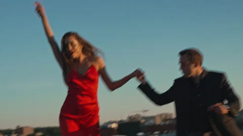 Couple in love on a romantic date dancing on the roof of a building at sunset Stock Footage 201426719