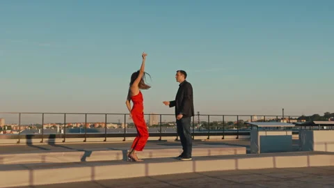 Couple in love on a romantic date dancing on the roof of a building at sunset Stock Footage 201426860