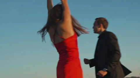 Couple in love on a romantic date dancing on the roof of a building at sunset Stock Footage 201427006