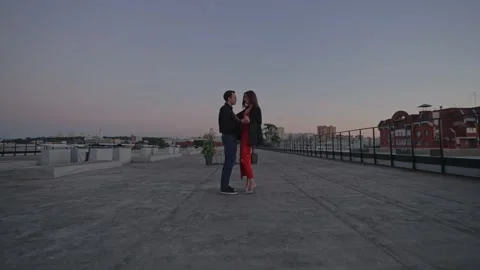 Couple in love on a romantic date dancing on the roof of a building at sunset Stock Footage 201427463