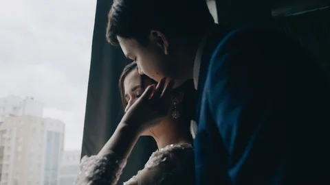 A couple in love stands in front of the window. Guy hugs his girlfriend Stock Footage 118467673