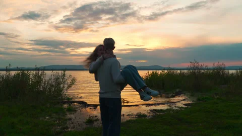 A couple in love at sunset. The guy whirled the girl on the shore of the lake. Stock Footage 314904296