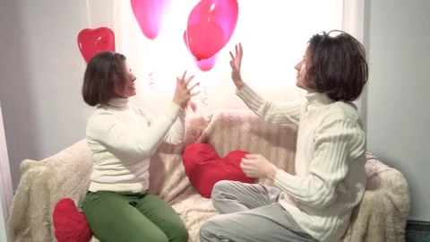 Couple of lovers playing with heart-shaped balloons in the bedroom Stock Footage 264273110