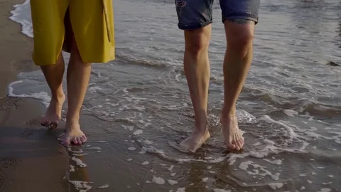Couple of lovers walking on the beach close-up. Cover your legs and legs Stock Footage 103404408