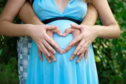 A couple lovingly places their hands over a pregnant belly Stock Photos