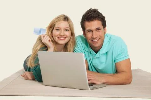 Couple lying and using laptop, smiling, portrait Stock Photos
