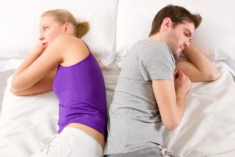 Couple lying in bed back-to-back having lovers' quarrel Stock Photos