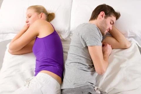 Couple lying in bed back-to-back Stock Photos