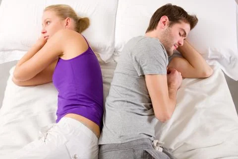 Couple lying in bed back-to-back having lovers' quarrel Stock Photos
