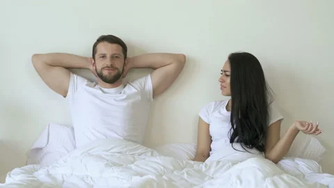 Couple lying in the bed. Girlfriend joking and checking potency. Video stock 107435336