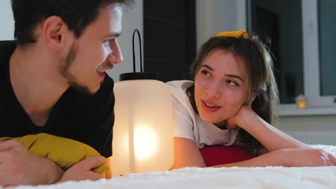 Couple lying on bed with a lamp between them an talking about christmas and Stock Footage 165295057
