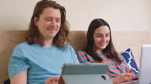 Couple lying in bed occupied with their own laptops. - slow motion Stock Footage 129462539