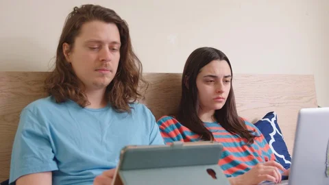 Couple lying in bed occupied with their own laptops. Stock Footage 129895606