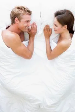 Couple lying in bed smiling Stock Photos