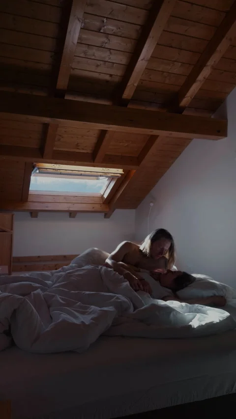 Couple lying in bed under attic window cozy romantic morning Stock Footage 332557894