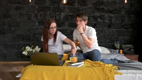 Couple Lying In Bed Use Laptop Computer Happy Smile Chatting Online and eating Stock Footage 75847162