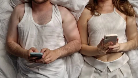 Couple Lying in Bed Using Smartphones Together Comfortably Stock Footage 311454833