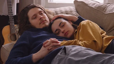 Couple lying down on a couch relaxing and watching TV. - slow motion Stock Footage 129466478